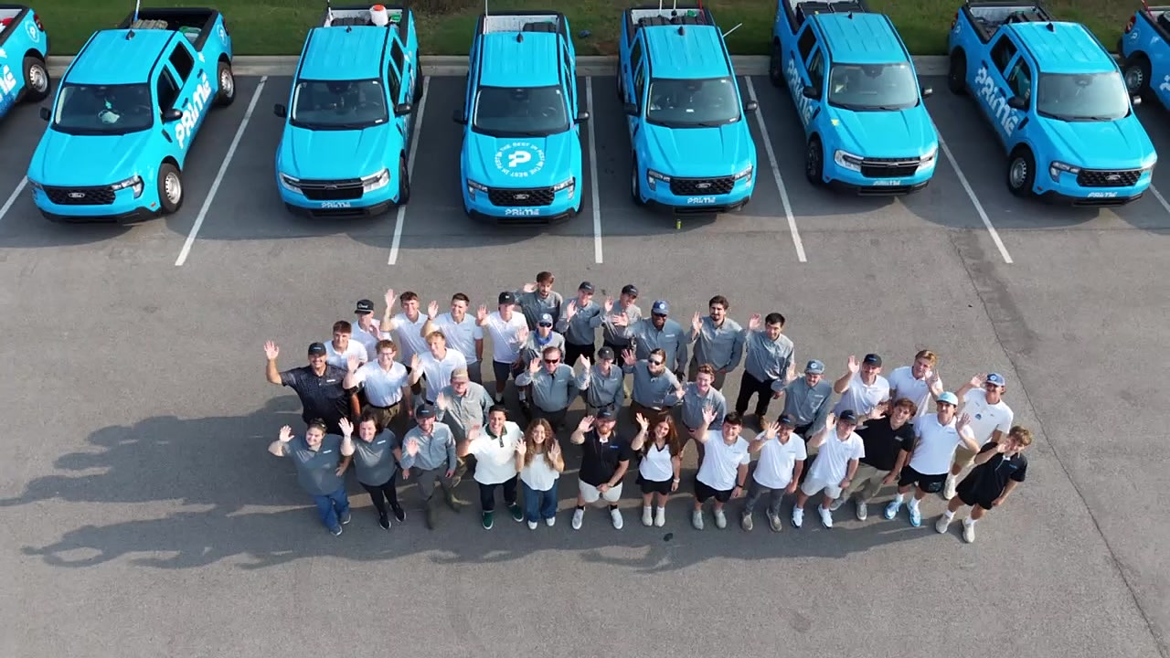 Aerial view of the Prime Pest Control team gathered in front of their fleet of bright blue service trucks in Huntsville, Alabama.